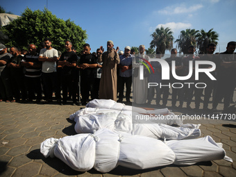 Palestinian men are praying over victims killed in an Israeli strike at the Aqsa Martyrs hospital in Deir el-Balah, on August 1, 2024, amid...