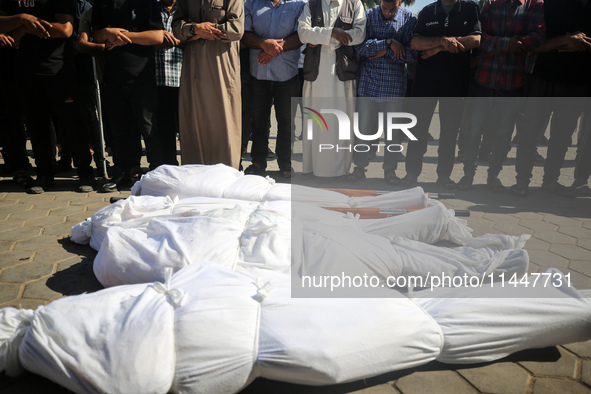 Palestinian men are praying over victims killed in an Israeli strike at the Aqsa Martyrs hospital in Deir el-Balah, on August 1, 2024, amid...