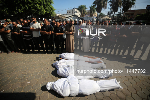 Palestinian men are praying over victims killed in an Israeli strike at the Aqsa Martyrs hospital in Deir el-Balah, on August 1, 2024, amid...