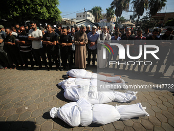 Palestinian men are praying over victims killed in an Israeli strike at the Aqsa Martyrs hospital in Deir el-Balah, on August 1, 2024, amid...