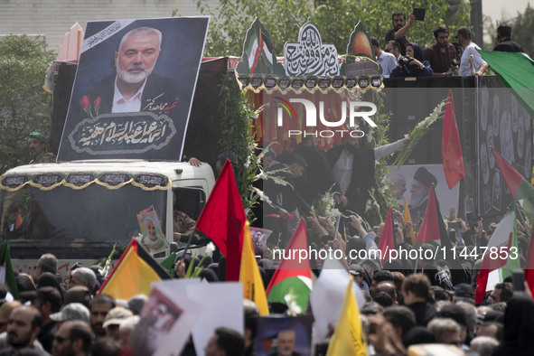 A truck is carrying the coffins containing the bodies of Hamas leader Ismail Haniyeh and his bodyguard Abu Shaaban through the crowd during...