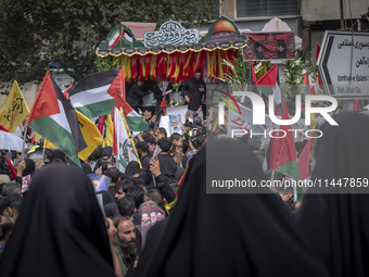 A truck is carrying the coffins containing the bodies of Hamas leader Ismail Haniyeh and his bodyguard Abu Shaaban through the crowd during...