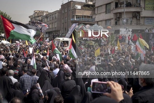 A truck is carrying the coffins containing the bodies of Hamas leader Ismail Haniyeh and his bodyguard Abu Shaaban through the crowd during...