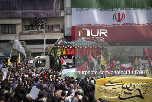 A truck is carrying the coffins containing the bodies of Hamas leader Ismail Haniyeh and his bodyguard Abu Shaaban through the crowd during...