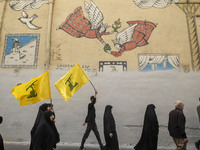 Iranian mourners are walking under a mural while two of them are carrying Lebanon's Hezbollah flag, during a funeral ceremony for Hamas lead...