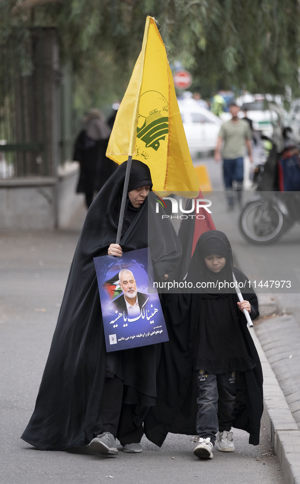 A veiled Iranian woman is carrying a Lebanon's Hezbollah flag and a portrait of Hamas leader Ismail Haniyeh during a funeral ceremony for hi...