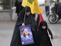 A veiled Iranian woman is carrying a Lebanon's Hezbollah flag and a portrait of Hamas leader Ismail Haniyeh during a funeral ceremony for hi...