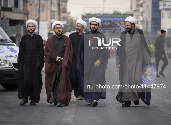 Iranian clerics are walking together along an avenue while one of them is carrying a portrait of Hamas leader Ismail Haniyeh, during a funer...