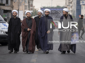 Iranian clerics are walking together along an avenue while one of them is carrying a portrait of Hamas leader Ismail Haniyeh, during a funer...