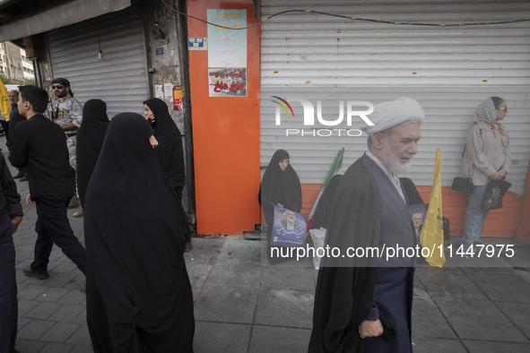 A veiled Iranian woman is holding a portrait of Hamas leader Ismail Haniyeh during a funeral ceremony for him and his bodyguard Abu Shaaban...