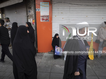 A veiled Iranian woman is holding a portrait of Hamas leader Ismail Haniyeh during a funeral ceremony for him and his bodyguard Abu Shaaban...