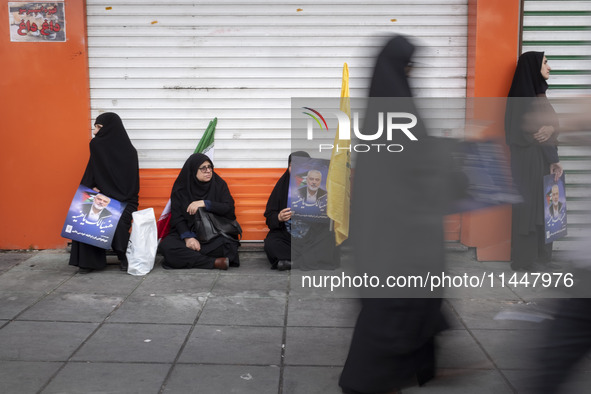 Veiled Iranian women are holding portraits of Hamas leader Ismail Haniyeh during a funeral ceremony for him and his bodyguard Abu Shaaban in...