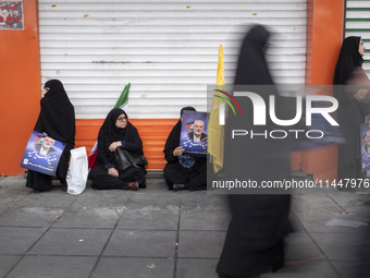 Veiled Iranian women are holding portraits of Hamas leader Ismail Haniyeh during a funeral ceremony for him and his bodyguard Abu Shaaban in...