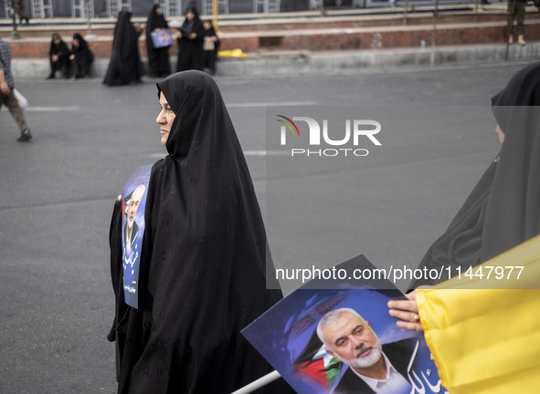 Two veiled Iranian women are carrying portraits of Hamas leader Ismail Haniyeh during a funeral ceremony for him and his bodyguard Abu Shaab...