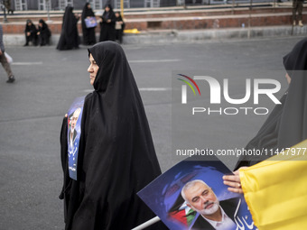 Two veiled Iranian women are carrying portraits of Hamas leader Ismail Haniyeh during a funeral ceremony for him and his bodyguard Abu Shaab...