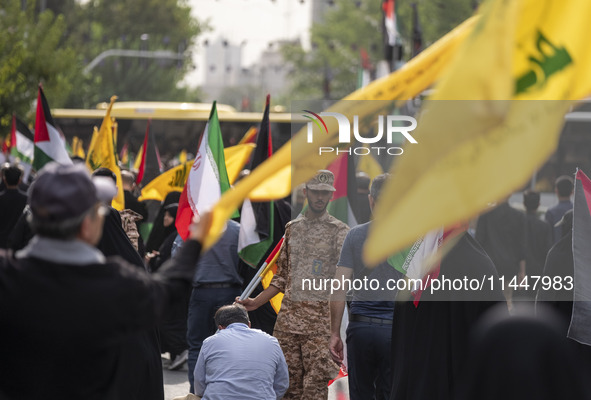 An Islamic Revolutionary Guard Corps (IRGC) military personnel is monitoring people during a funeral ceremony for Hamas leader Ismail Haniye...