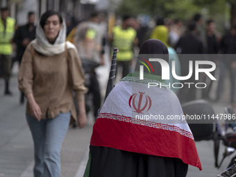 A veiled Iranian woman is wearing an Iranian flag while arriving to participate in a funeral ceremony for Hamas leader Ismail Haniyeh and hi...