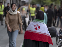 A veiled Iranian woman is wearing an Iranian flag while arriving to participate in a funeral ceremony for Hamas leader Ismail Haniyeh and hi...