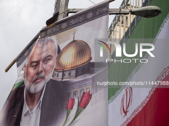 A banner featuring a portrait of Hamas leader Ismail Haniyeh is being hung next to an Iranian flag during a funeral for him and his bodyguar...