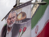 A banner featuring a portrait of Hamas leader Ismail Haniyeh is being hung next to an Iranian flag during a funeral for him and his bodyguar...