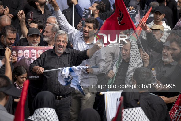 An Iranian man is shouting anti-U.S. and anti-Israeli slogans while burning an Israeli flag during a funeral ceremony for Hamas leader Ismai...