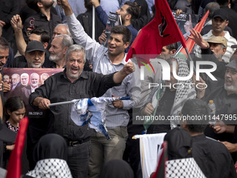 An Iranian man is shouting anti-U.S. and anti-Israeli slogans while burning an Israeli flag during a funeral ceremony for Hamas leader Ismai...