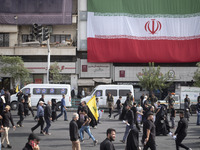 Iranian mourners are walking under a giant Iranian flag while participating in a funeral ceremony for Hamas leader Ismail Haniyeh and his bo...