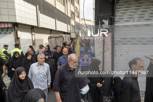 An Iranian man is carrying a portrait of Hamas leader Ismail Haniyeh during a funeral ceremony for him and his bodyguard Abu Shaaban in Tehr...