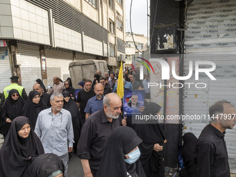 An Iranian man is carrying a portrait of Hamas leader Ismail Haniyeh during a funeral ceremony for him and his bodyguard Abu Shaaban in Tehr...