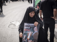 A veiled Iranian woman is carrying an anti-Israeli poster while participating in a funeral ceremony for Hamas leader Ismail Haniyeh and his...