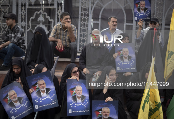 Iranian mourners are holding portraits of Hamas leader Ismail Haniyeh during a funeral ceremony for him and his bodyguard Abu Shaaban in Teh...