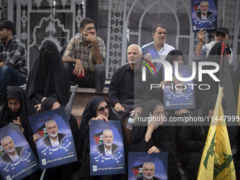 Iranian mourners are holding portraits of Hamas leader Ismail Haniyeh during a funeral ceremony for him and his bodyguard Abu Shaaban in Teh...