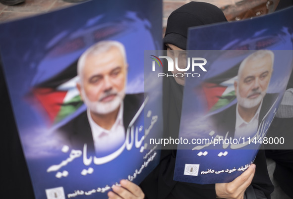 Iranian mourners are holding portraits of Hamas leader Ismail Haniyeh during a funeral ceremony for him and his bodyguard Abu Shaaban in Teh...