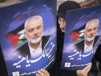 Iranian mourners are holding portraits of Hamas leader Ismail Haniyeh during a funeral ceremony for him and his bodyguard Abu Shaaban in Teh...