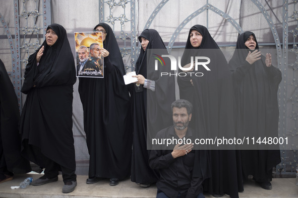 Iranian mourners are beating themselves while one of them is holding a poster featuring portraits of the former commander of the Islamic Rev...