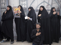 Iranian mourners are beating themselves while one of them is holding a poster featuring portraits of the former commander of the Islamic Rev...