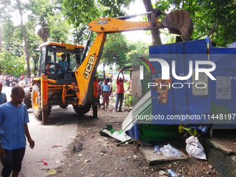 A JCB is breaking the shops during an eviction drive by Siliguri Municipal Corporation as temporary shopkeepers are setting up their stalls...