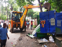 A JCB is breaking the shops during an eviction drive by Siliguri Municipal Corporation as temporary shopkeepers are setting up their stalls...