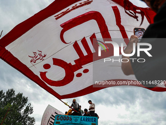 Shia devotees are raising flags during the 25th Muharram procession in Baramulla, Jammu and Kashmir, India, on August 1, 2024. (