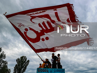 Shia devotees are raising flags during the 25th Muharram procession in Baramulla, Jammu and Kashmir, India, on August 1, 2024. (