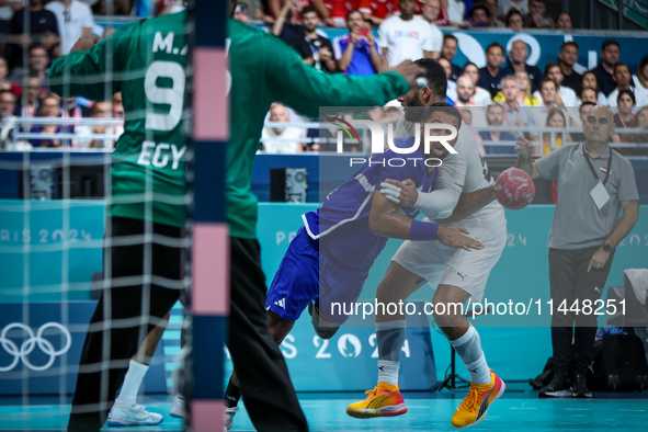 Melvyn Richardson of the France team is shooting at the goal against Ahmed Adel of the Egypt team during the men's Handball Preliminary Roun...