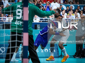 Melvyn Richardson of the France team is shooting at the goal against Ahmed Adel of the Egypt team during the men's Handball Preliminary Roun...