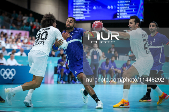 Melvyn Richardson of the France team is shooting at the goal against Ali Zein and Ibrahim Elmasry of the Egypt team during the men's Handbal...