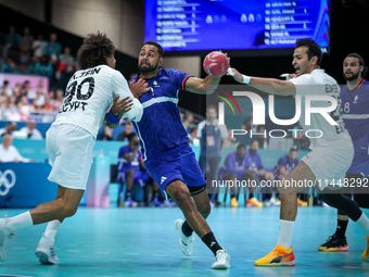 Melvyn Richardson of the France team is shooting at the goal against Ali Zein and Ibrahim Elmasry of the Egypt team during the men's Handbal...