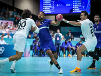 Melvyn Richardson of the France team is shooting at the goal against Ali Zein and Ibrahim Elmasry of the Egypt team during the men's Handbal...