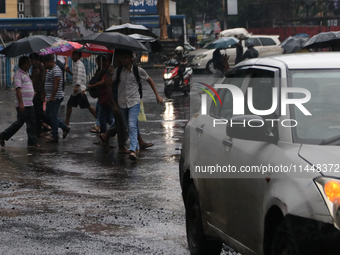 People are crossing a road during monsoon rain in Kolkata, India, on August 1, 2024. (