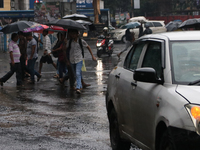 People are crossing a road during monsoon rain in Kolkata, India, on August 1, 2024. (