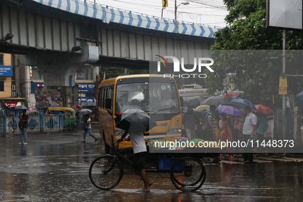 A fruit seller is holding an umbrella while crossing the busy road during monsoon rain in Kolkata, India, on August 1, 2024. 