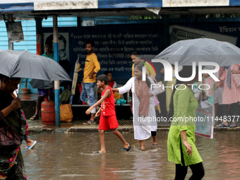 Women are holding umbrellas and crossing a road during monsoon rain in Kolkata, India, on August 1, 2024. (