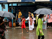 Women are holding umbrellas and crossing a road during monsoon rain in Kolkata, India, on August 1, 2024. (